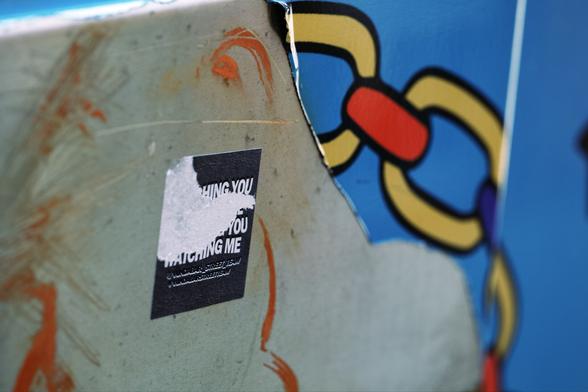 Close up shot of a utility box showing a peeling wrap, a torn sticker, and some graffiti.