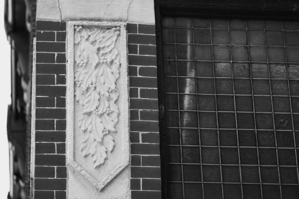 Looking up at some fancy stonework on the corner of a brick building.