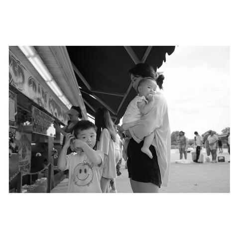 Street photo of a kid and his mother holding his baby brother, taken at the fish market in Washington DC