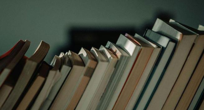 A stock image of a selection of well-worn books on a bookshelf. None of the titles are visible.