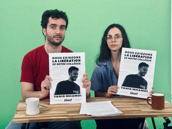 Ost et Modiie tenant deux affiches avec Yanis Mhamdi à l’image. Il y a écrit : nous exigeons la libération de notre collègue
