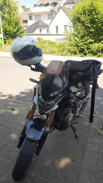 Ein Motorrad von vorne, an dem am Spiegel ein weißer Helm hängt
