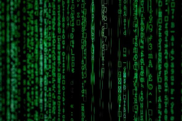 Des lignes de code se suivent verticalement. Elles semblent faire référence au film Matrix.