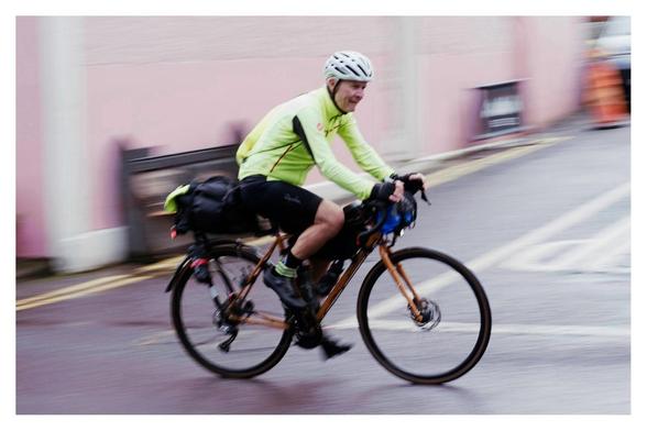 Cyclist in motion on the Trans Atlantic Way cycle race passing the world famous Levis Corner House.