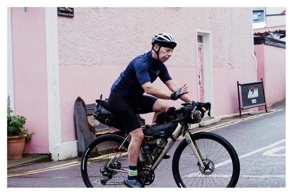 Cyclist waves on the Trans Atlantic Way cycle race passing through Ballydehob.
