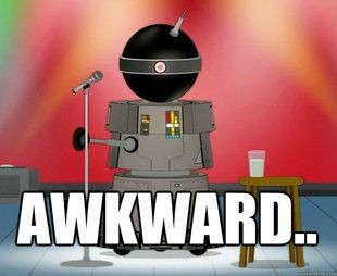 A robot with a round black head, a single electronic eye, and a canister body with a robotic arm. The robot is in front of a microphone on a stage. There is a glass of water on a wooden table behind the robot.
Text: AWKWARD