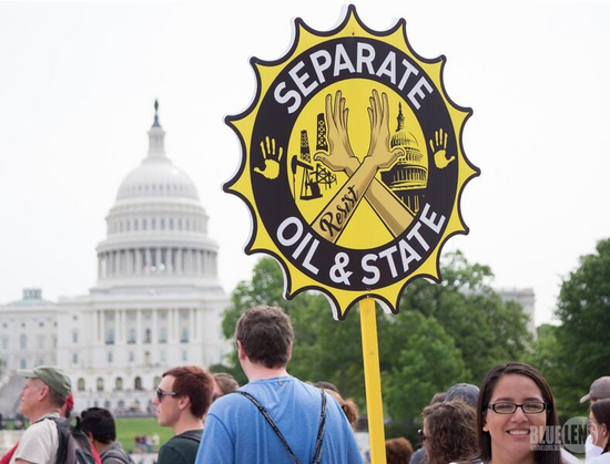 Image shows a placard at a protest saying "separate oil and state".