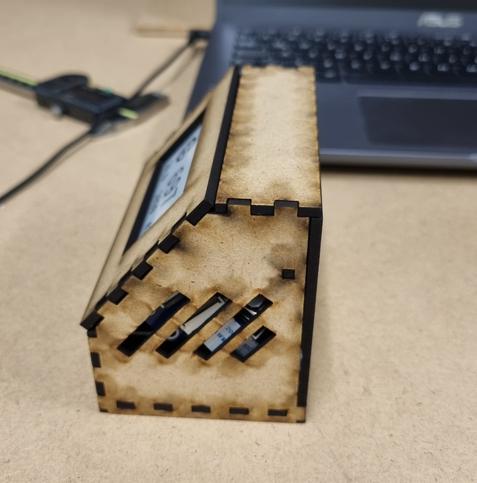 Seitenansicht einer Holzbox. Die einzelnen Wände sind mit finger joints ineinander gesteckt. In der Seitenwand sind Schlitze ausgeschnitten.