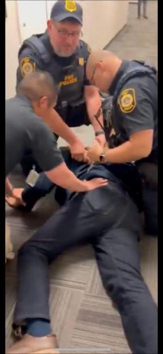 three officers pushing Senator Padilla face down into the ground and zip tying his wrists behind his back.