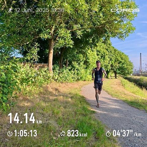 Ein Läufer auf einem sandigen Fußweg, ihm (mir) ist sichtlich warm. Links im Bild Hecken und Bäume, rechts im Bild ist eine Bahntrasse zu erahnen.