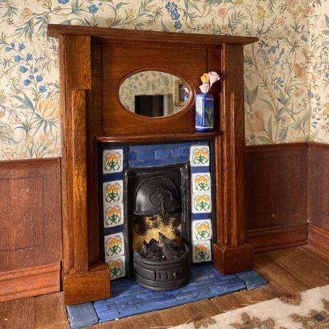 A dolls house fire surround with tulip design yellow, pink and green tiles and plain blue spacers which match the hearth. The wooden surround is French polished to a nice shine and an oval mirror is in the centre.