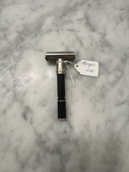 A metal adjustable Gillette safety razor with a black handle. A $2.50 price tag is attached to it.