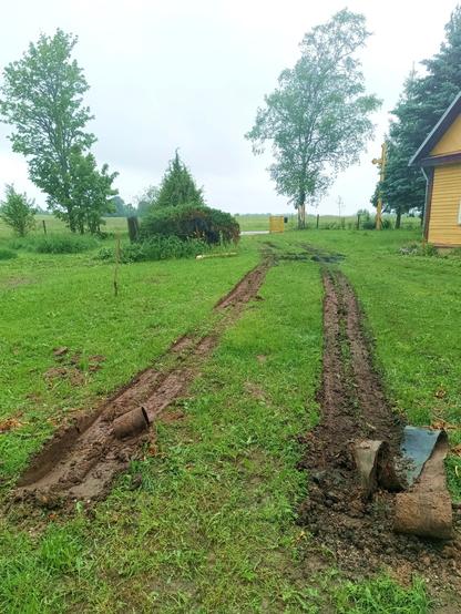 The aftermath in the yard. Two double tracks from the truck have chewed up the grass, beginning with a muddy pit where the tyres spun. Some rubber conveyor belt is pushed into the mud. Further ahead, another section of the driveway is chewed up by four tractor tyres spinning in a few places until they got a grip. The gate is open.