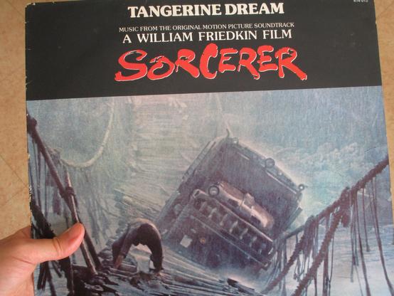 Ma main gauche tenant le 33T de la BO du film de Sorcerer de Friedkin par le groupe Tangerine Dream, illustré par la séquence incroyable du passage du camion le plus dangereux du monde sur une passerelle non adaptée, sous un déluge de pluie, au-dessus d'un torrent, un homme se cramponnant à quatre pattes sur les lattes