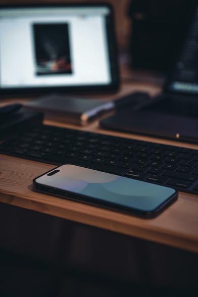 A phone on a desk, with a screen in the background.

Photo by Rickie-Tom Schünemann from Pexels: https://www.pexels.com/photo/smartphone-and-keyboard-16564513/