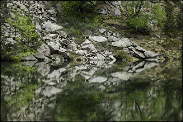 CAT
Hores menudes i grans alhora
Escoltem un murmuri.
L'aigua no es belluga
Les roques dibuixen
un trencaclosques misteriós.
Torno a parar l'orella:
Res, només l'immensitat.
Tot dorm i somia a l'estany.

OC
Oras pichonas e grandas a l'encòp
Ausissèm un mormolh.
L'aiga se desplaça pas
Las ròcas trason
un enigma misteriós.
Remetèri l'aurelha:
Res, sonque immensitat.
Tot dormís e sòmia dins l'estanh.