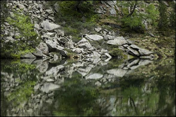 CAT
Hores menudes i grans alhora
Escoltem un murmuri.
L'aigua no es belluga
Les roques dibuixen
un trencaclosques misteriós.
Torno a parar l'orella:
Res, només l'immensitat.
Tot dorm i somia a l'estany.

OC
Oras pichonas e grandas a l'encòp
Ausissèm un mormolh.
L'aiga se desplaça pas
Las ròcas trason
un enigma misteriós.
Remetèri l'aurelha:
Res, sonque immensitat.
Tot dormís e sòmia dins l'estanh.