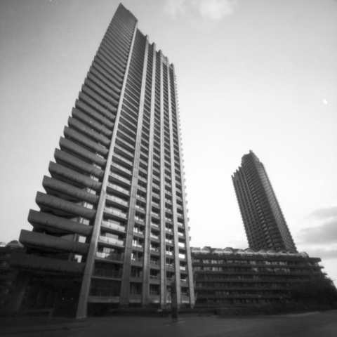 Photograph looking up at one of the Barbican towers from the ground, a second tower in the distant background