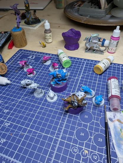 Twelve squig miniatures, some painted some not. Three are blue. Four are magenta. One is a yellowish brown that will eventually be yellow. I hope.