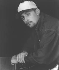 Retrato en blanco y negro de un hombre con gorra y chaqueta, mirando hacia la cámara con una expresión seria.