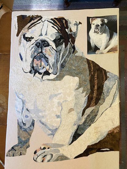 Fabric collage portrait of a white with brown markings English bulldog done in fabric.