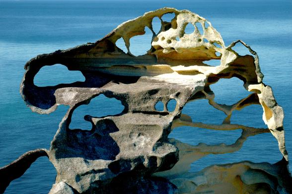 Honeycomb sandstone with smooth blue ocean behind.