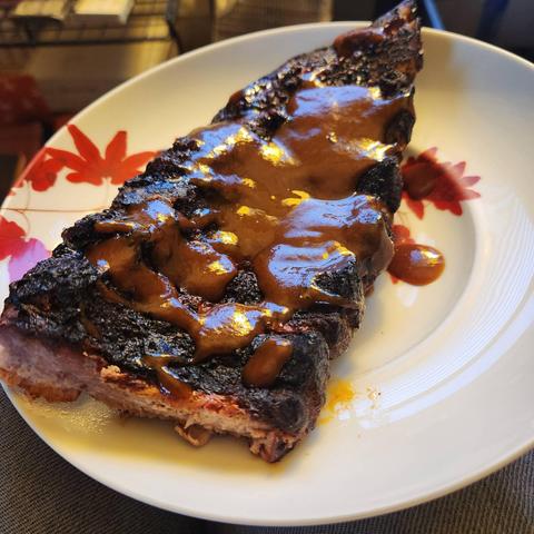 Half a rack of tender ribs covered in sauce.