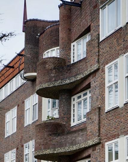 Petits balcons dessinant des virgules sur une façade en brique des années 20.