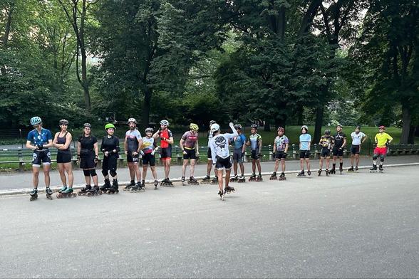 Photo of 17 inline skaters in a line, as their coach at the side gives them final instructions before they set off for paceline work.