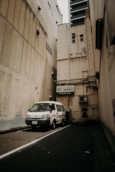 photo of a minivan parking between large buildings on a tiny parking lot