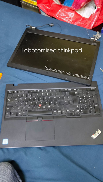 thinkpad on my bed, with the screen disconnected from the keyboard part. the text "lobotomised thinkpad" is written on top of the screen