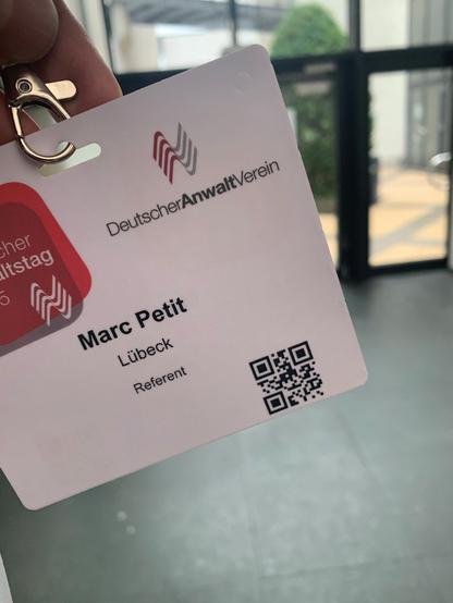 Rot-weißes Namensschild vom Deutschen Anwaltverein. Aufschrift: Marc Petit – Lübeck – Referent.