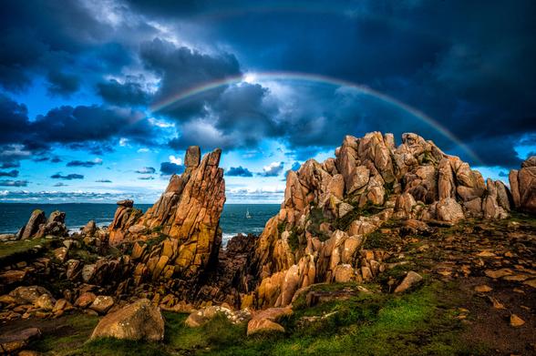 Felsformation in der Bretagne mit Regenbogen.