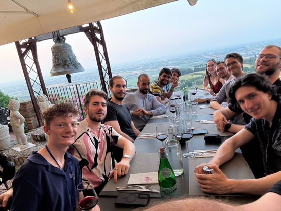 STudents sitting on a long table on the terrace at dinner.