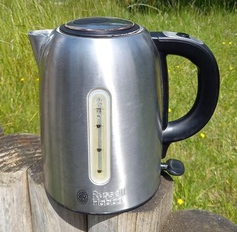 A stainless steel kettle with black handle and lid.