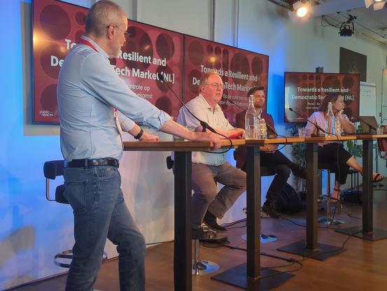 Sprekers panel voor de beeldschermen met de tekst "Towards a Resilient and Democratic Tech Market,
Eis de controle over onze digitale toekomst