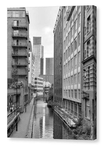 Black and white portrait photograph showing tall buildings either side of a canal.  The image is shown printed upon a box canvas.
