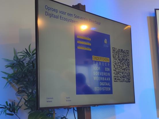 Slide op het scherm met "oproep aan de overheid: Investeer in een soeverein en weerbaar digitaal ecosysteem" en een QR code naar de link in de toot.