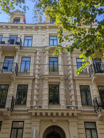 Façade d'immeuble ornée de frises et de colonnes, dans les tons beiges, avec des fenêtres hautes