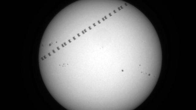 Die Sonne im Weißlicht. Davor als Silhouette die ISS, mehrere Einzelaufnahmen invertiert summiert.