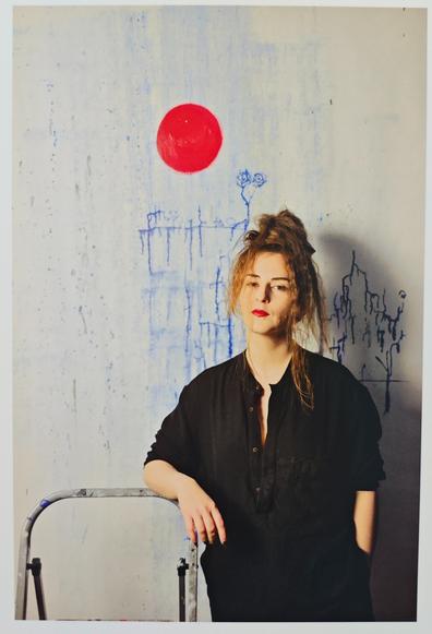 frau steht vor wand, wo blaue adern gemalt sind und ein roter kreis.