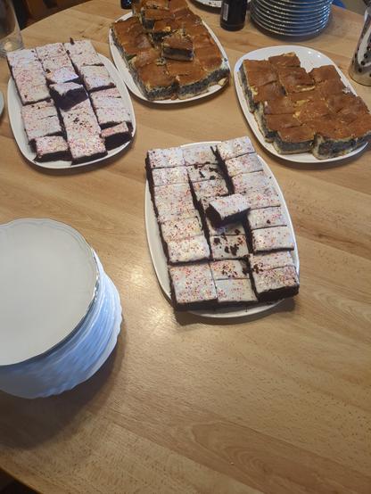 Photo of a table with 4 plates with cake and a stack of plates.