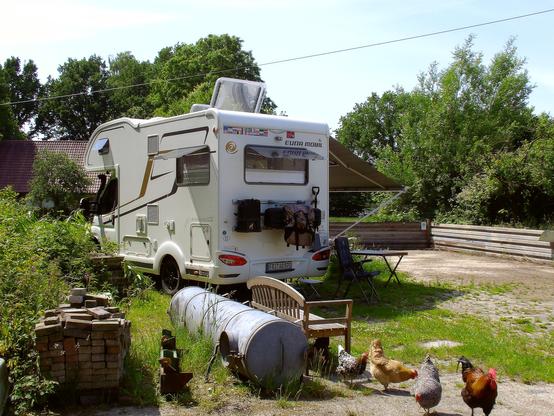 Unser wohnmobil auf einem Bauernhof. Im Vordergrund sind Hühner.