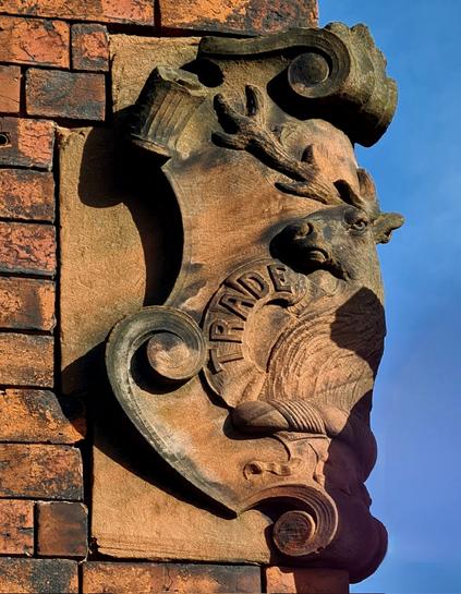 A terracotta trademark shield featuring a stag's head on the corner of a former Victorian industrial building.