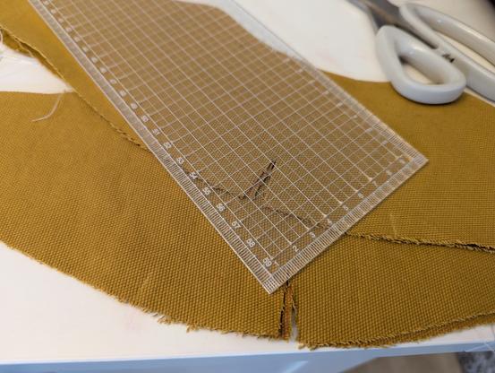 Close up of one end on top of some yellow fabric, showing the millimetre divisions around the edges