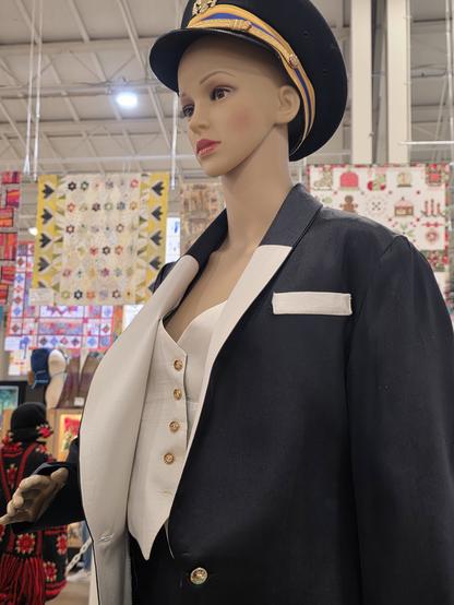 This is a tuxedo, with vest. It's made in black and cream silk. The pants are black, and are non-controversial. the vest is cream silk and is reversible. The other side is a green silk with square designs on it, that change with the angle of the light. They chose to show it with the cream side facing the viewer. The buttons on the cream side are gold, and really pop in the overhead lighting. The jacket is black silk (matching the pants) but tuxedos can have a very long vertical collar. I did this for this pattern, but the upper 20% of the collar is the same black silk as the jacket, but the lower 80% of the collar is the same fabric as the vest, so it's very angular and lego-like, and unexpected. I did the pocket welt on the lefthand side of the jacket in the same cream silk, for further contrast. 

The curators chose to put a pilot's hat on the female mannequin that the tuxedo was on. They couldn't have known this in advance, but maybe someone knew what they were getting. I had modified this tuxedo for my daughter to wear to prom. It looks better on a female mannequin. They had male mannequins, but put a traditional male outfit on a female mannequin. I choose to believe they figured it out from the modifications made to the pattern, and had no issue with presenting it as it was sewn. Thank you San Diego County Fair.