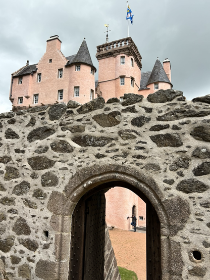 A shot of the castle roofline in the background with the remains of a barmekin (fort) wall in the foreground.