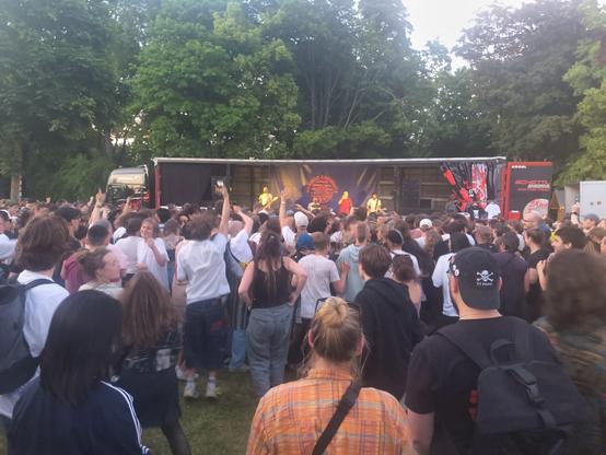 Große tanzende Menschenmenge vor einem offenen LKW Auflieger von dem aus die Band Team Scheiße spielt.