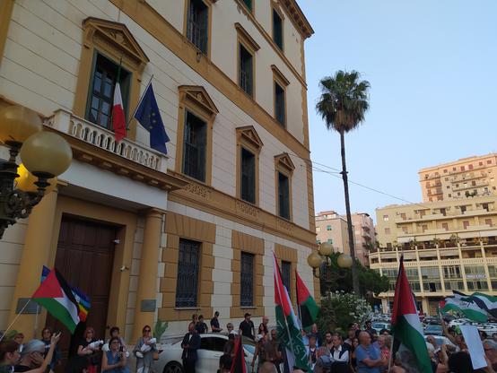 Diverse persone con bandiere palestinesi fuori dalla prefettura di Agrigento. Sul palazzo svettano la bandiera dell'Italia e dell'UE