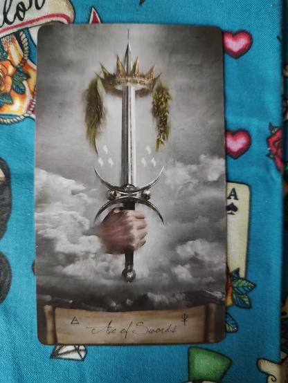 Card from the Heaven and Earth Tarot deck. 
Ace of Swords. 
A hand emerges from the clouds holding a sword pointed upward. There is a crown in the sword's tip.